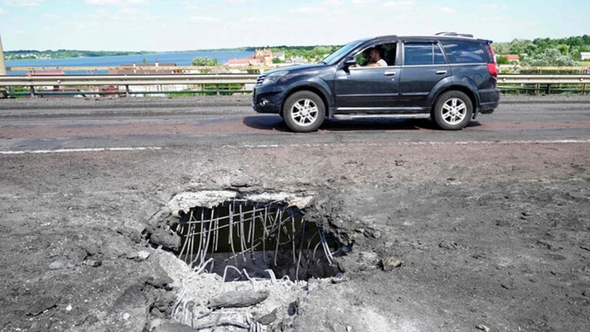 Ô tô di chuyển qua một miệng hố trên cầu Antonovsky ở Kherson vào tháng 7/2022, sau khi tuyến đường tiếp tế quan trọng cho lực lượng Nga bị quân đội Ukraine nhắm mục tiêu. Ảnh: AFP