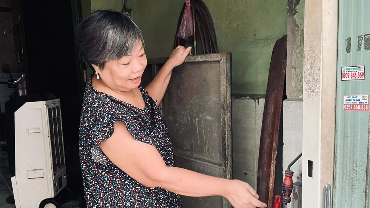 Bà Nguyệt Hằng giới thiệu tấm vách sắt chống nước tràn vào nhà, chiều 30/9. Ảnh:Ngọc Ngân