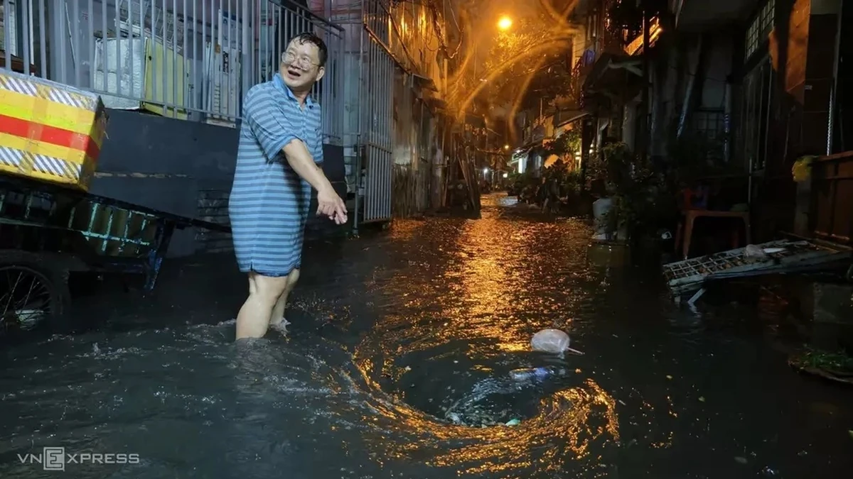 Một số người dân ở trong hẻm đường Chu Văn An mang sọt đi thu gom rác bị cuốn theo xoáy nước làm tắc miệng cống, tháng 9/2026. Ảnh:Đình Văn